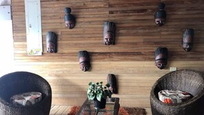 A room with wooden walls, a potted plant, and two wicker chairs. - Hotel Yurupary (Leticia)