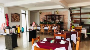 A dining area with wooden tables and chairs, a counter with coffee makers, and a decorative wall with a painting. - Hotel Yurupary (Leticia)