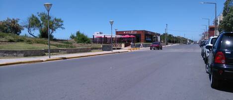 A street view with a building labeled "MAVERICK" in the distance, featuring outdoor seating with umbrellas.