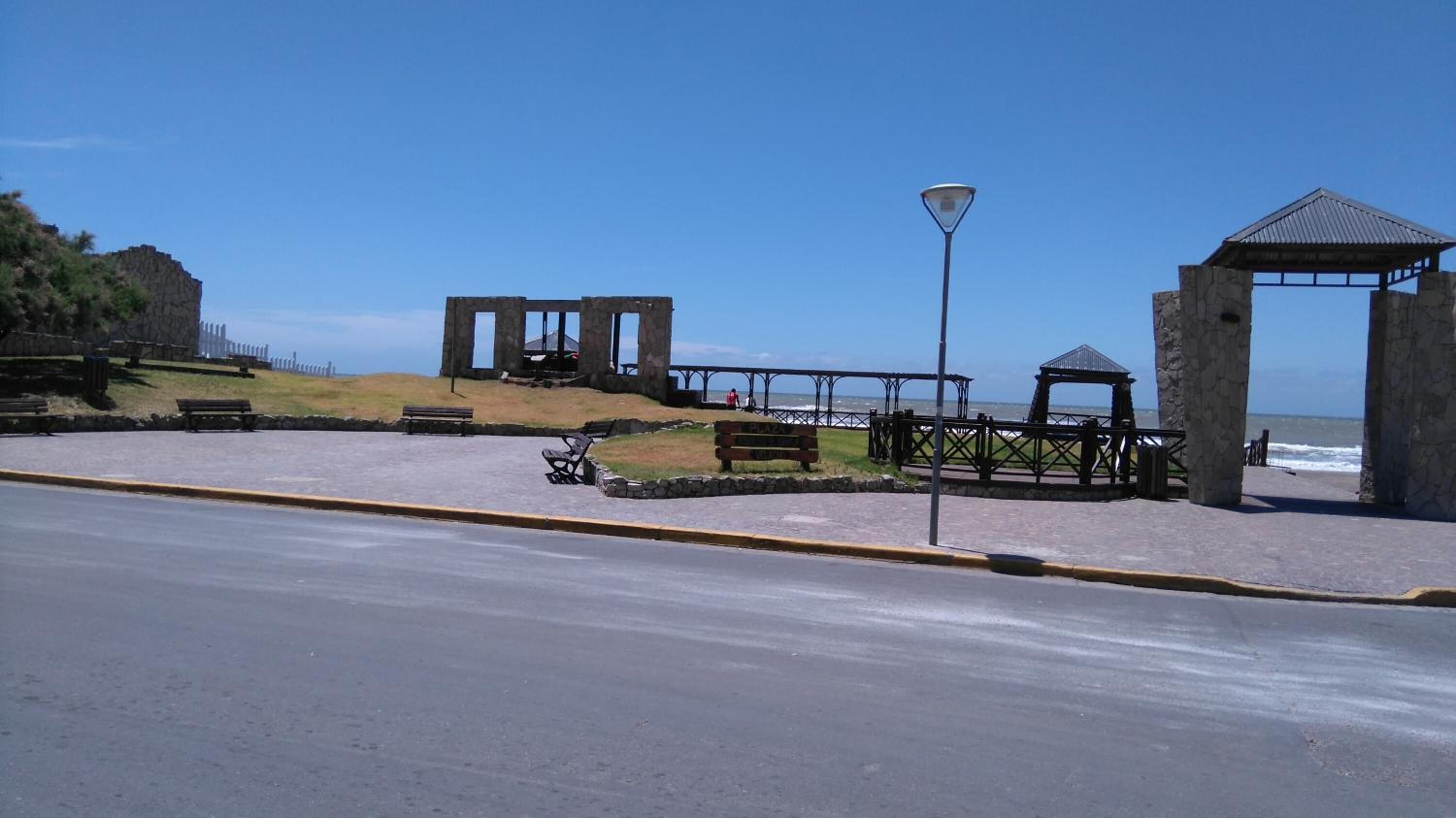 Une promenade en bord de mer agrémentée de structures en pierre, de bancs et d’un lampadaire.
