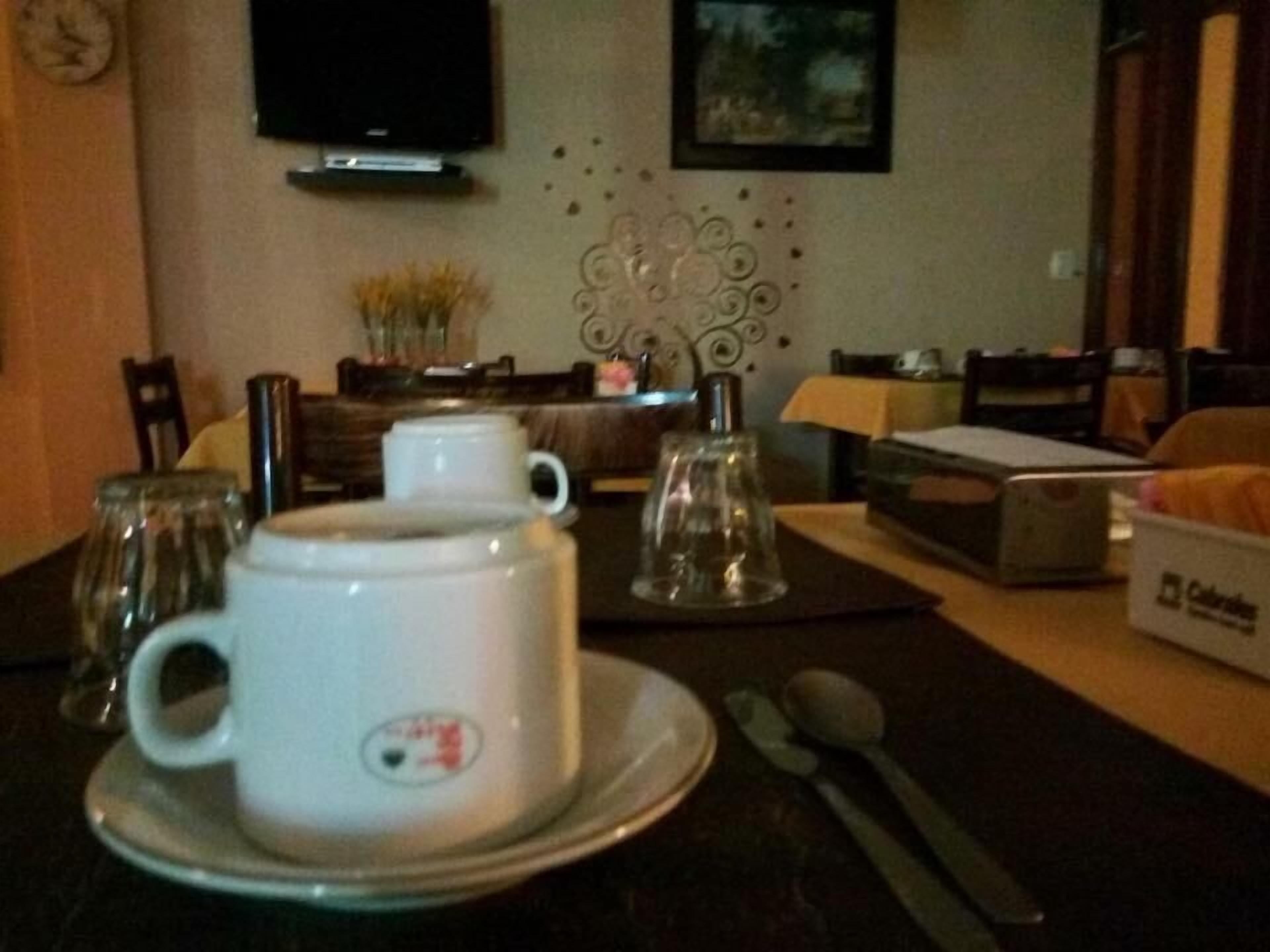 A dining area with a table set for two, featuring a white coffee cup and saucer, a glass jar, and a box of Coleslaw.