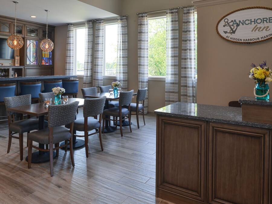 A modern kitchen with a bar area, dining chairs, and a large island.