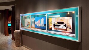 A hallway with a digital display featuring images of rooms and amenities.