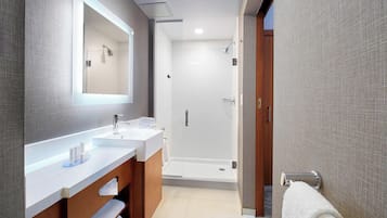 Un baño moderno con un espejo grande, dos lavamanos, una ducha y un perchero para toallas.