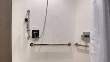 A modern shower area with a grab bar, a handheld showerhead, and a white shower curtain.