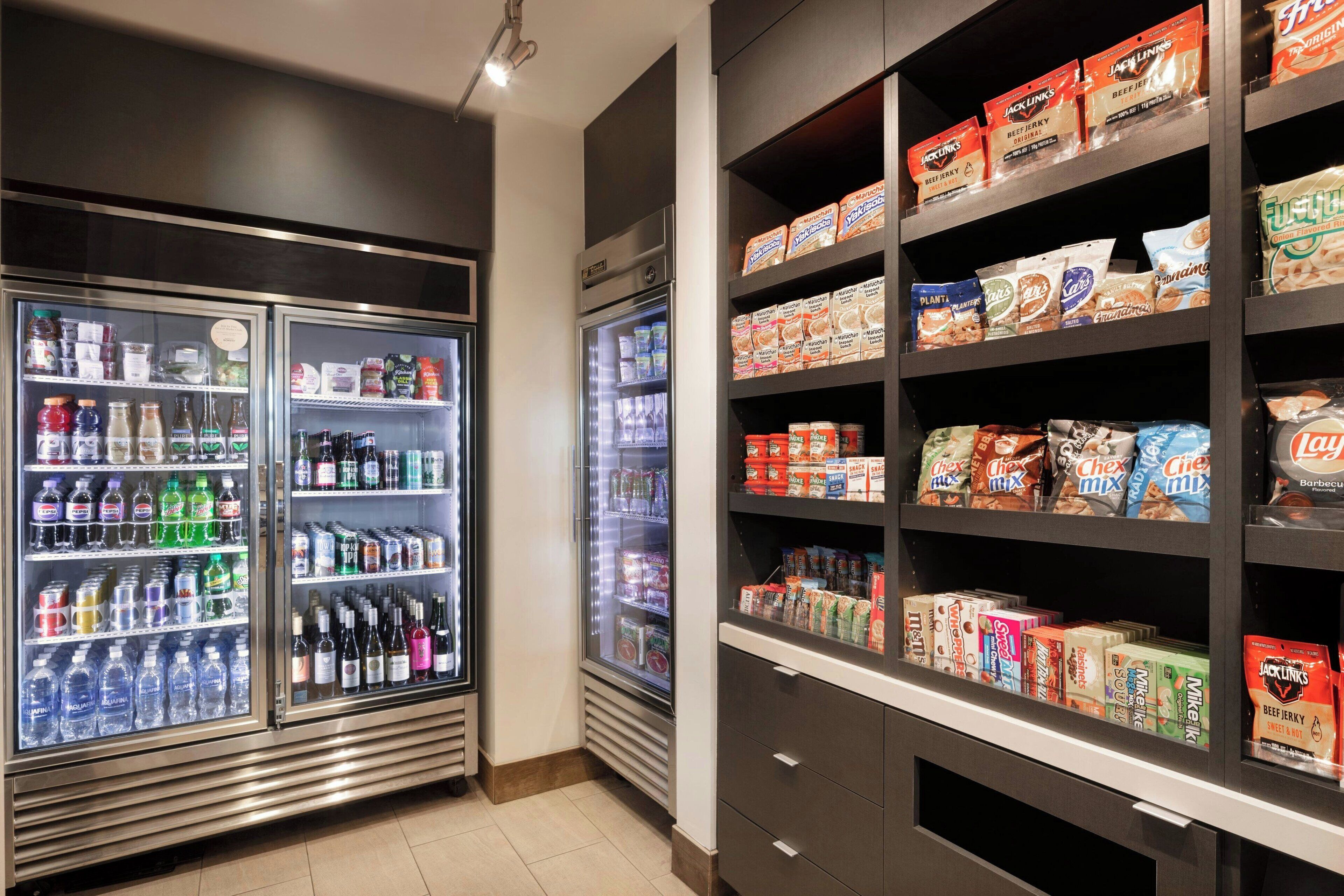 A refrigerated display case with various beverages and a shelf stocked with packaged food items.
