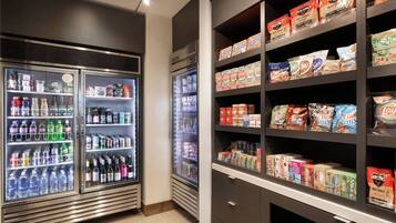 A refrigerated display case with various beverages and a shelf stocked with packaged food items.