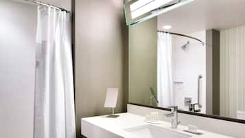 Un baño moderno con un lavamanos blanco, un espejo, una cortina de ducha y un cabezal de ducha de mano.