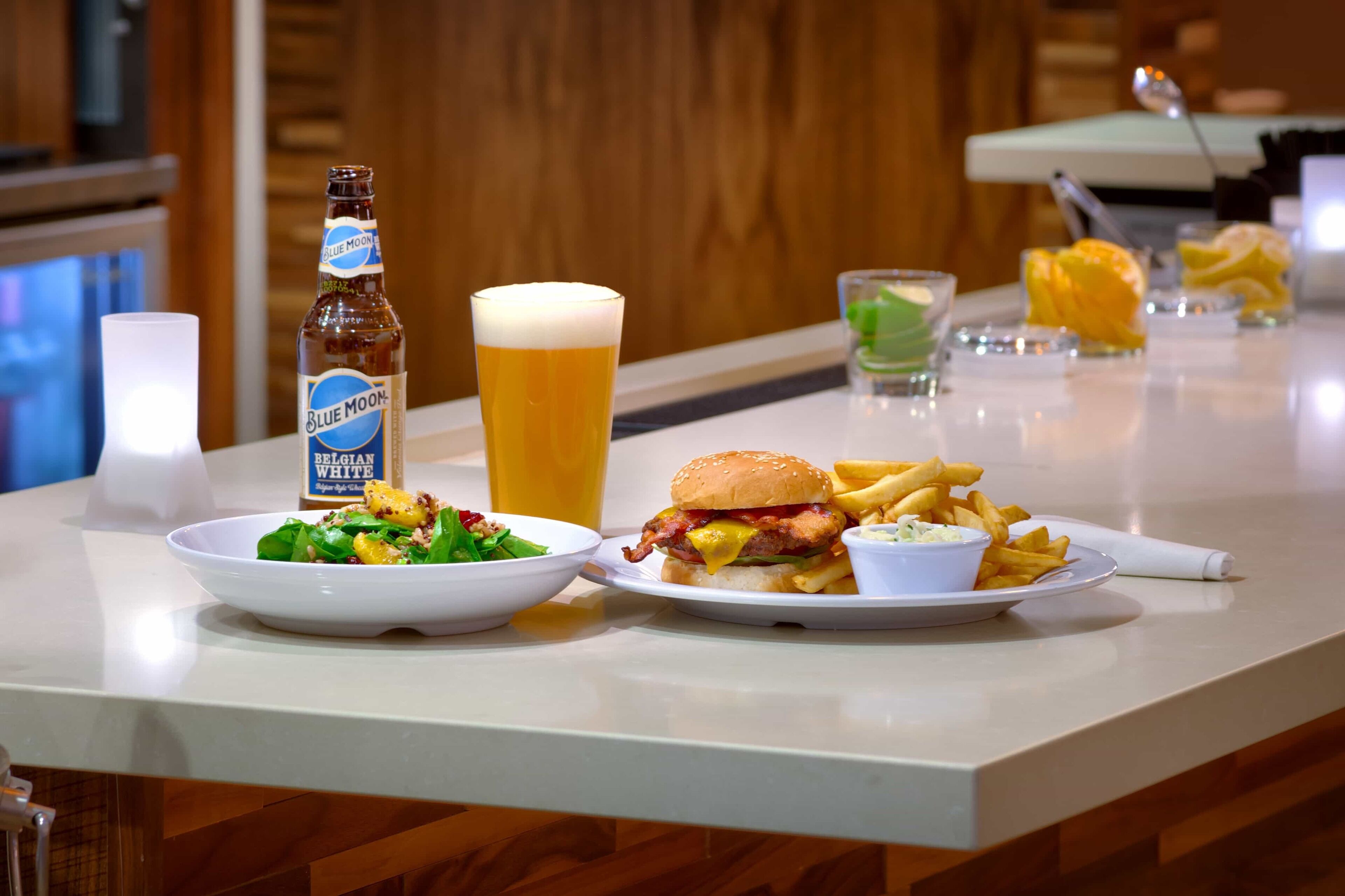 Una comida con hamburguesa, papas fritas y cerveza sobre una barra.