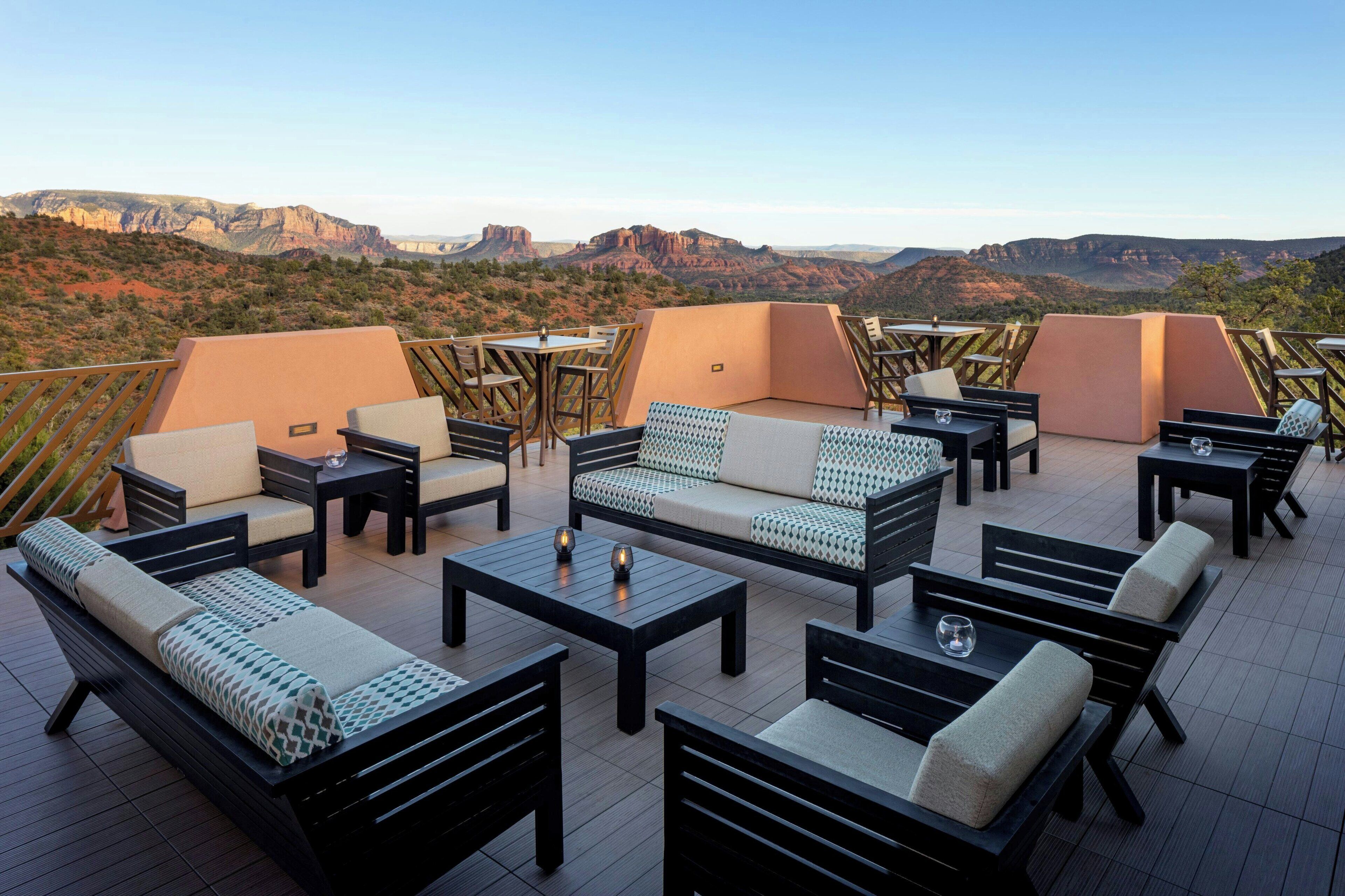 Terraza en la azotea con mobiliario exterior, incluyendo sofás y mesas, con vistas a un paisaje montañoso.