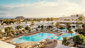 Un complexe hôtelier doté de plusieurs piscines, de chaises longues et de palmiers.