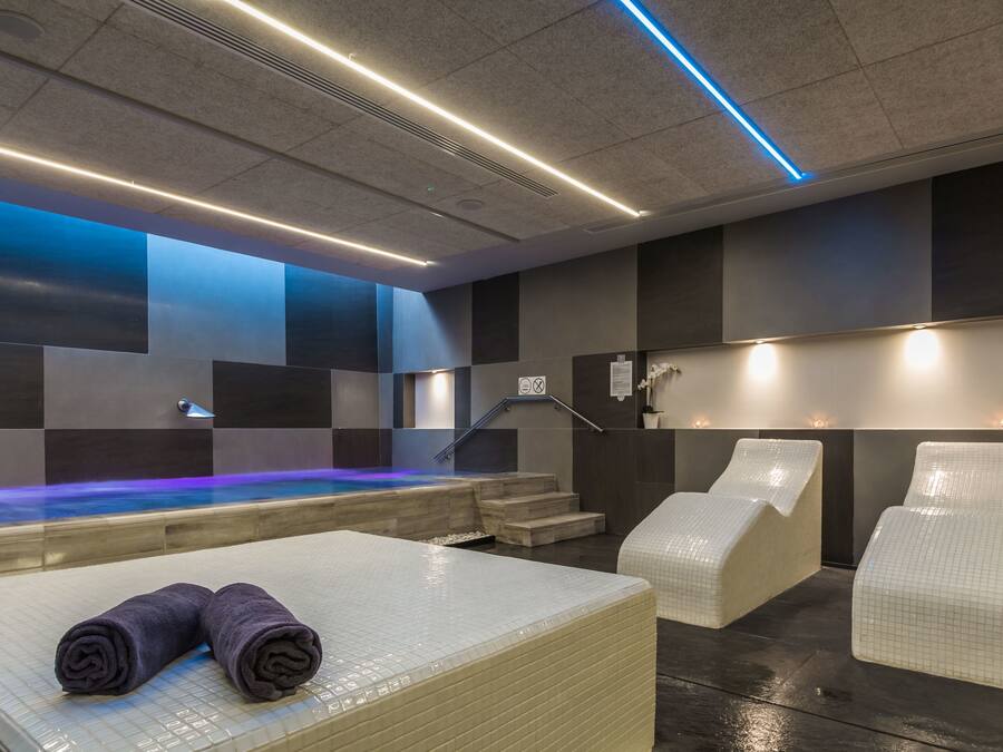Ein modernes Spa mit Pool, Liegebereichen und einer Rezeption.