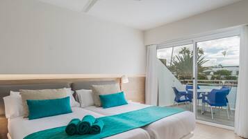 Una habitación de hotel con cama, ventilador de techo y balcón con sillas azules.