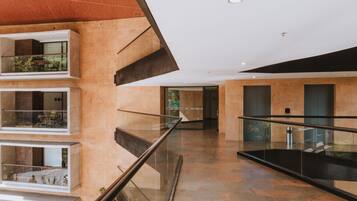 Un interior moderno con varios niveles, barandillas de vidrio y una combinación de iluminación natural y artificial.
