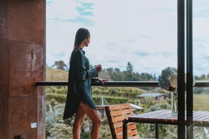 A woman standing by a balcony with a view of a rural landscape. - Travelers Rio Verde Living Suites (Rionegro)