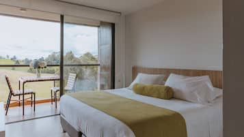 Un dormitorio con una cama grande, vistas al exterior y una mesa con sillas.
