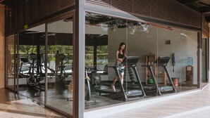 A modern gym with glass walls, treadmills, and exercise equipment. - Travelers Rio Verde Living Suites (Rionegro)