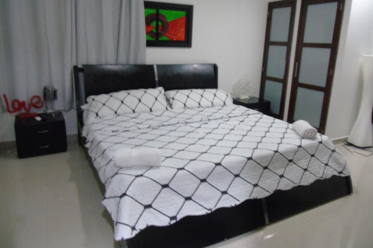 Un dormitorio con cama, mesita de noche, una obra de arte en la pared y armario.