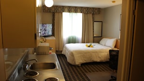 A hotel room with a bed, a desk with a sink, and a window with curtains. - Hillcrest Motel (Swan Hills)