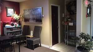 A hotel lobby with a reception desk, two armchairs, a large painting, a potted plant, and a Christmas wreath. - Hillcrest Motel (Swan Hills)