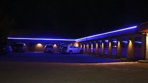 A motel with a row of rooms, each with a door and a window. - Hillcrest Motel (Swan Hills)