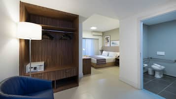 A hotel room with a bed, a desk, a chair, a wardrobe, and a bathroom.