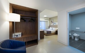 A hotel room with a bed, a desk, a chair, a wardrobe, and a bathroom. - Matiz Multi Suítes (Duque de Caxias)