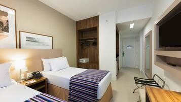 Una habitación de hotel con dos camas, un armario de madera, un escritorio y un televisor.
