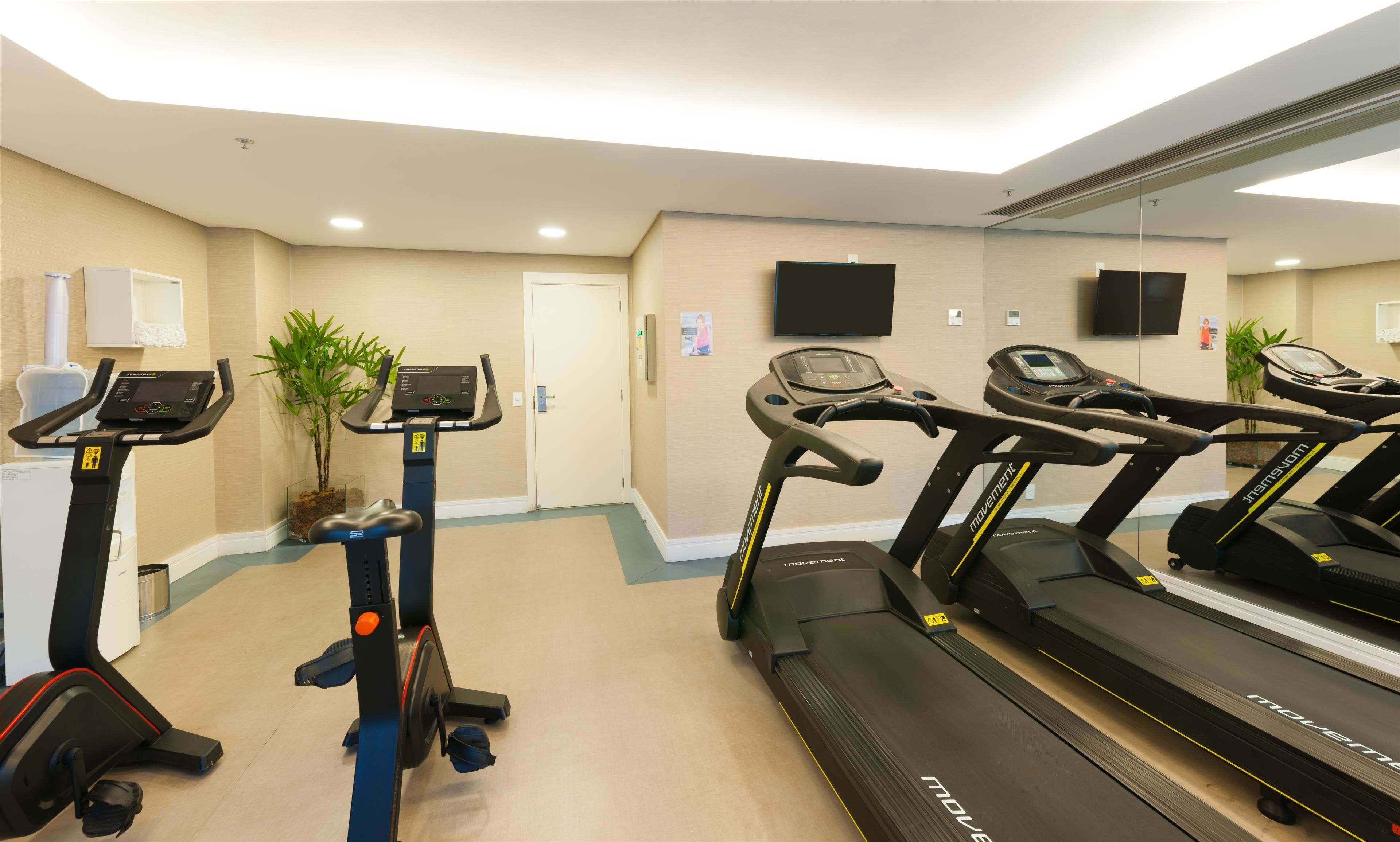 Un gimnasio con cintas de correr, elípticas y una bicicleta estática.