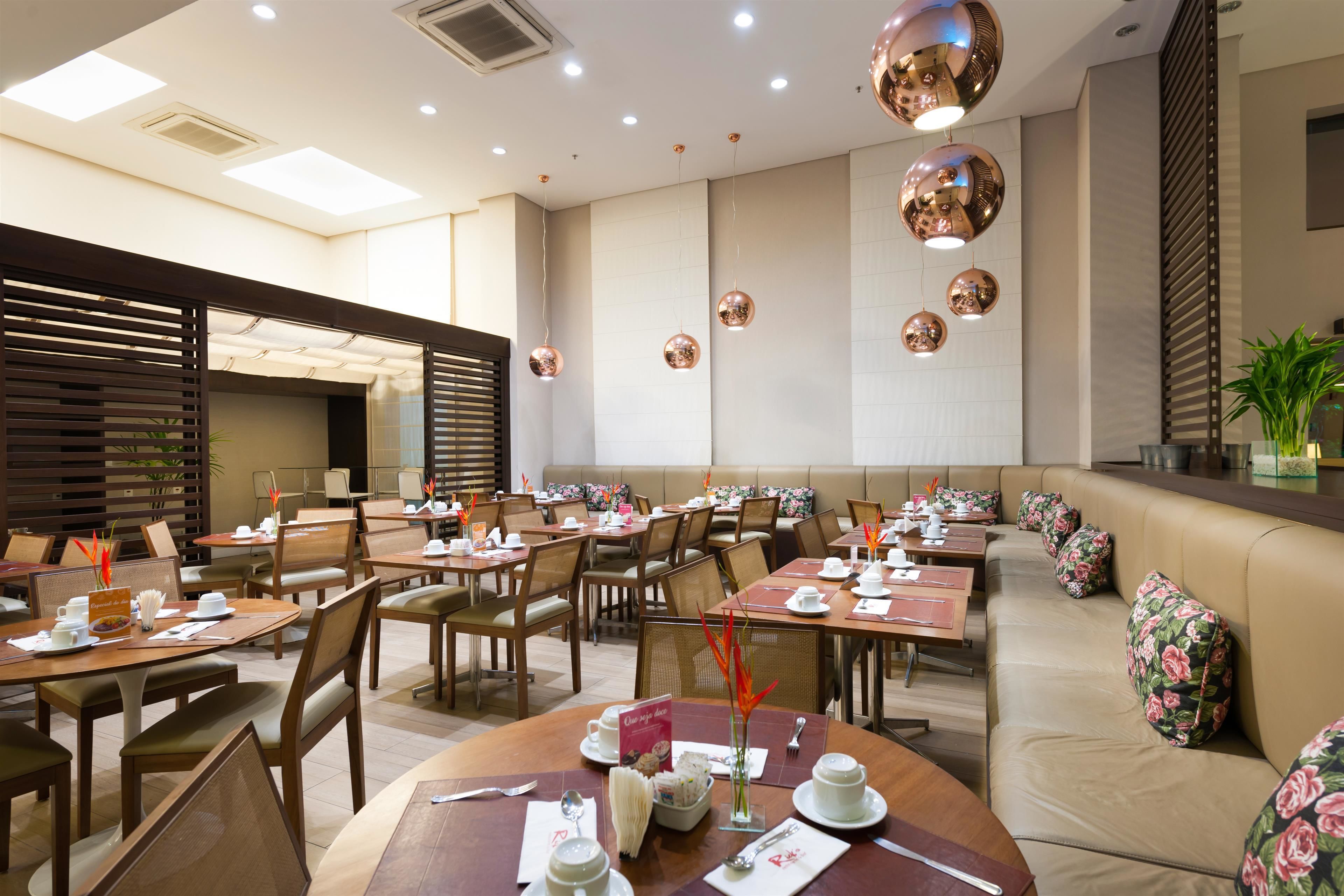 A restaurant with round tables, chairs, and a long bench seating area.