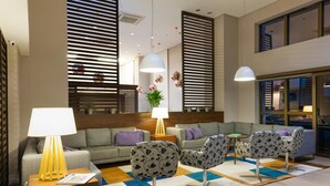 Una sala de estar moderna con un sofá, dos sillones, una mesa de centro y una lámpara.