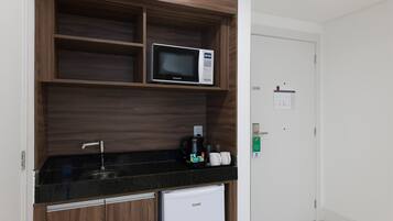 Uma cozinha compacta equipada com micro-ondas, cafeteira e pequena geladeira.