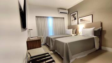 Une chambre d’hôtel avec deux lits, un bureau, une chaise, une télévision et un appareil de climatisation.