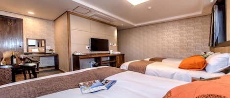 Ein Hotelzimmer mit zwei Betten, einem Schreibtisch, einem Fernseher und einem Badezimmer.