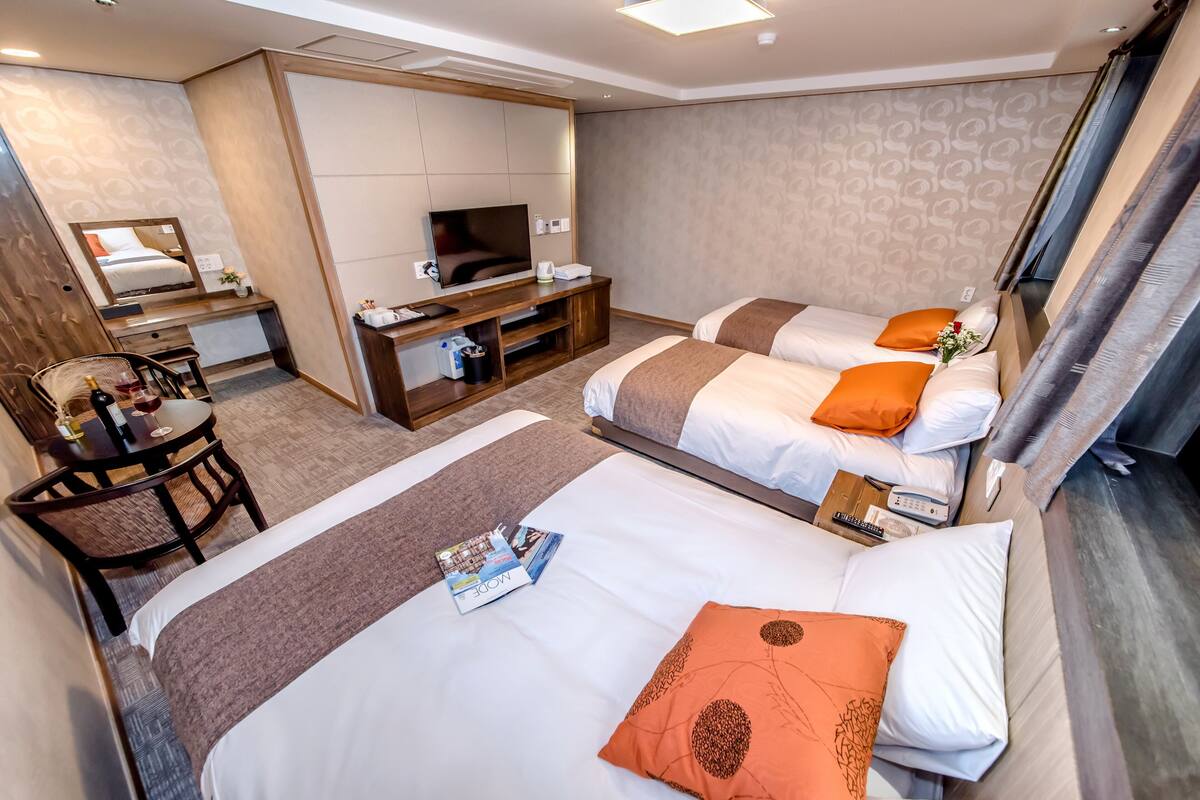 Une chambre d’hôtel avec deux lits, un bureau, une télévision et une chaise.