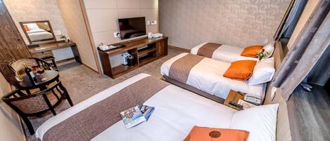A hotel room with two beds, a desk, a TV, and a chair.