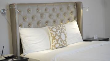A neatly made bed with a tufted headboard, a bedside table with a lamp, and a small sign on the nightstand.