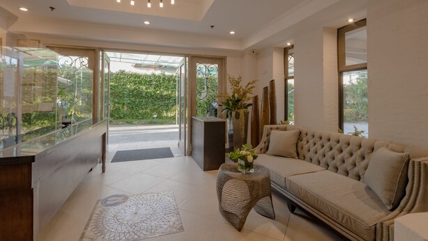 A modern interior with a sofa, a glass reception desk, and a large window with a view of greenery.