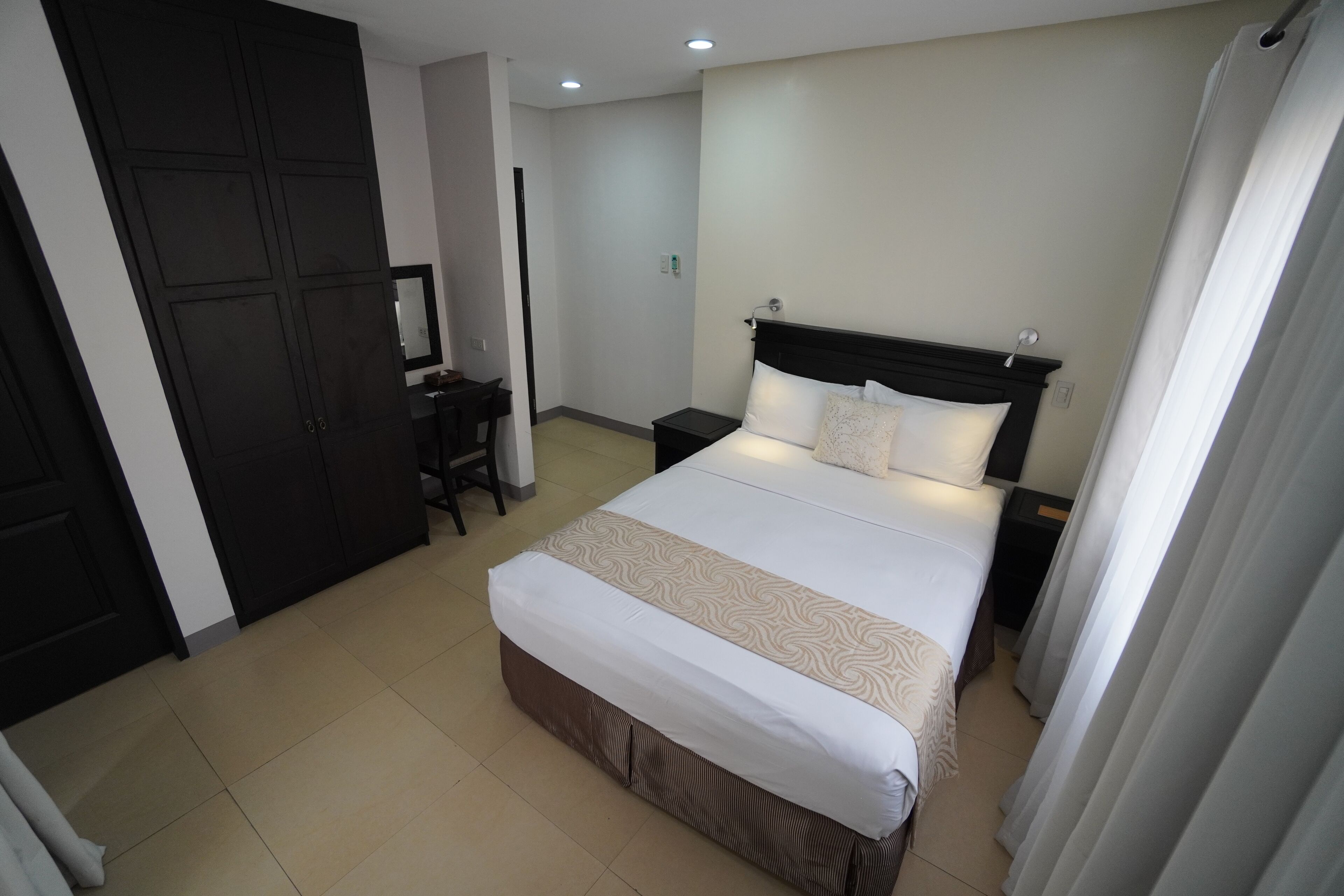 A hotel room with a large bed, a desk, a wardrobe, and a mirror.