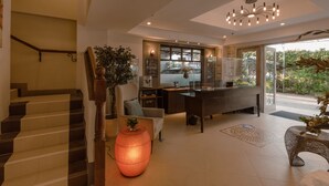 A modern interior with a staircase, a reception desk, and a large window offering a view of greenery.