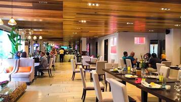 A restaurant with wooden ceiling panels, dining tables with chairs, and a bar area.