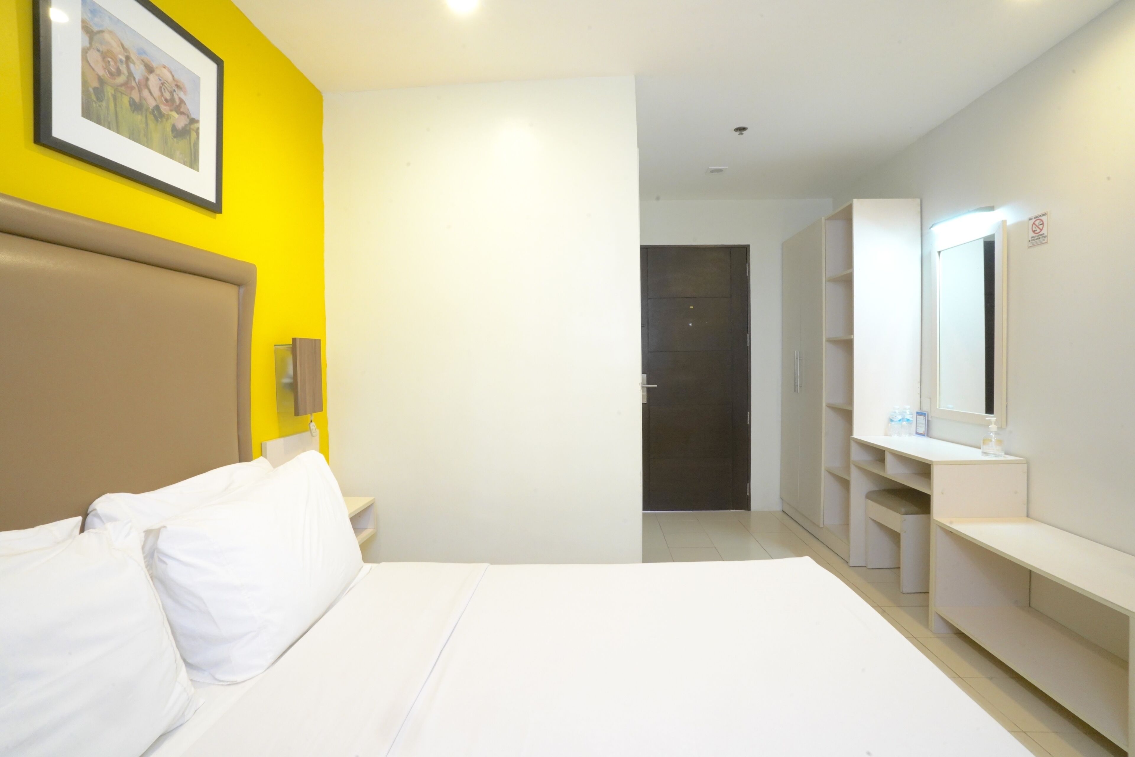 Une chambre d’hôtel comprenant un lit, une table de chevet, un miroir et une armoire.