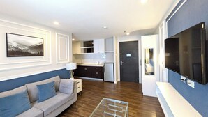 A modern living room with a sofa, a TV, and a kitchen area in the background. - Tom's Cabin Hotel (Cebu City)