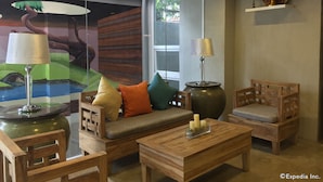 A cozy room with a sofa, two chairs, a coffee table, and a lamp. - Tom's Cabin Hotel (Cebu City)