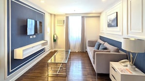A modern living room with a flat-screen TV, a glass coffee table, a sofa, and a lamp. - Tom's Cabin Hotel (Cebu City)