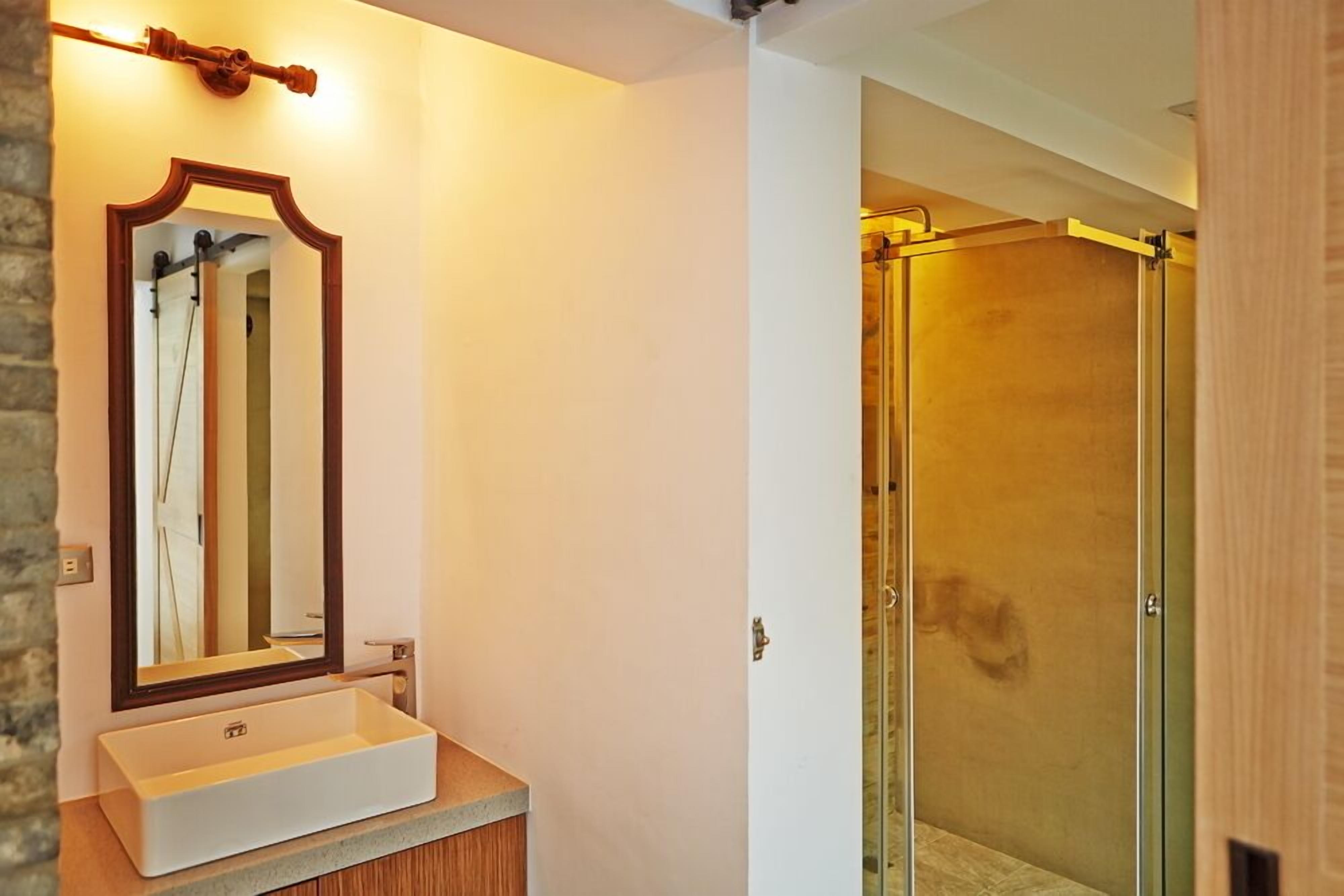 A bathroom with a white sink, a mirror with an ornate frame, and a glass shower enclosure.