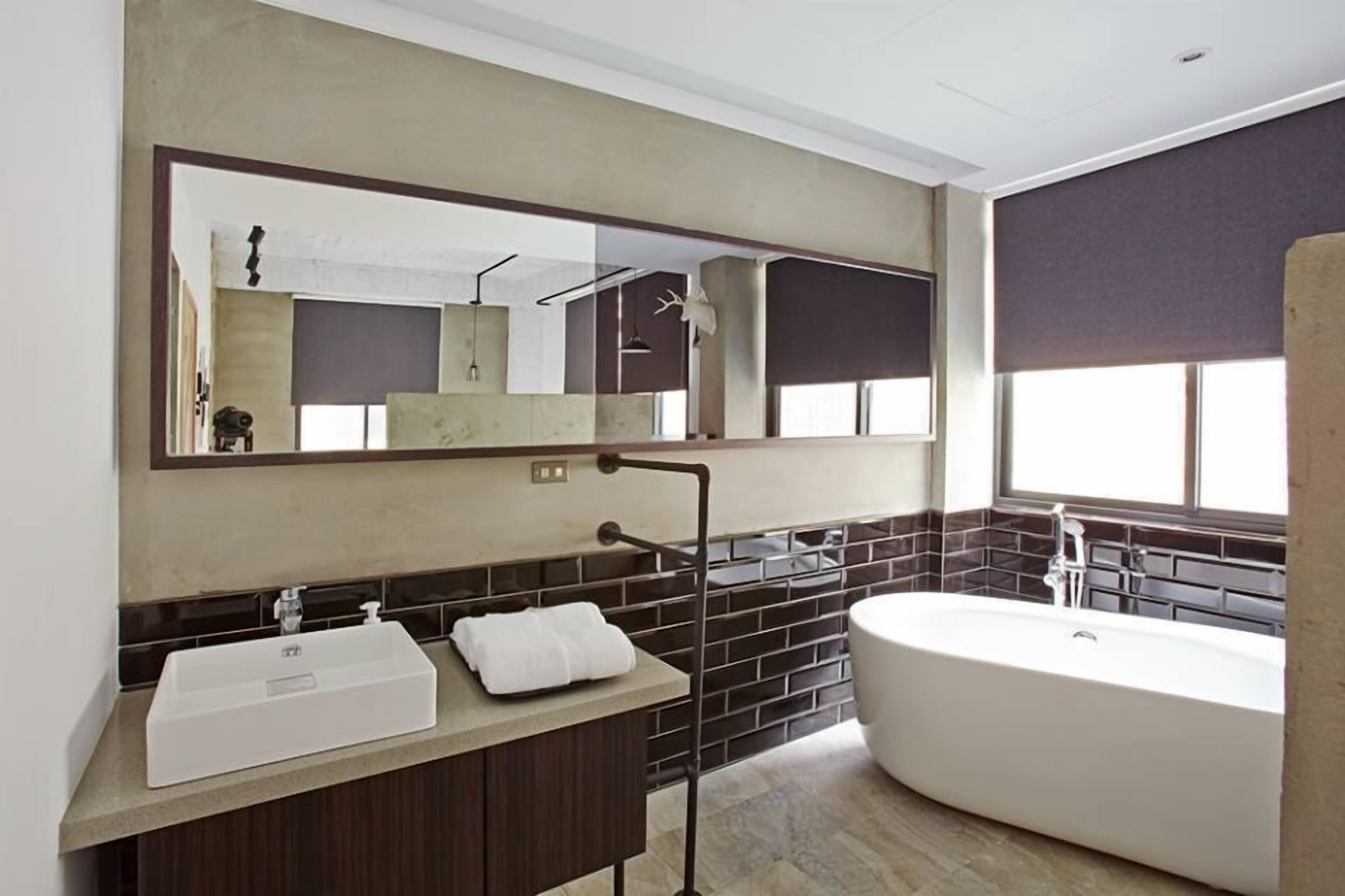 A modern bathroom with a large mirror, a freestanding bathtub, and a vanity with a sink.