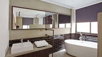 A modern bathroom with a large mirror, a freestanding bathtub, and a vanity with a sink.