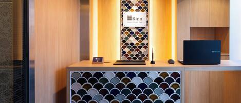 A reception desk with a sign reading "Rinn Sanjo Obashi East" and a laptop on it.