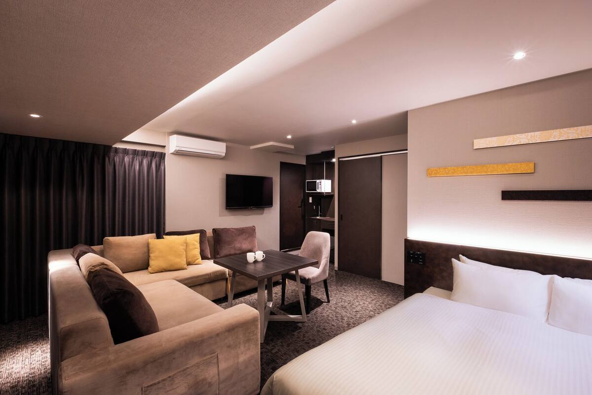 Une chambre d’hôtel avec un lit, un canapé, une table et un téléviseur.
